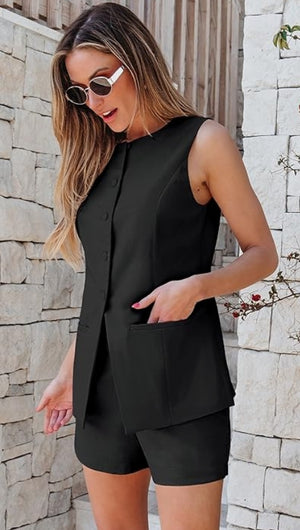 Woman wearing a black sleeveless top and shorts against a stone wall.