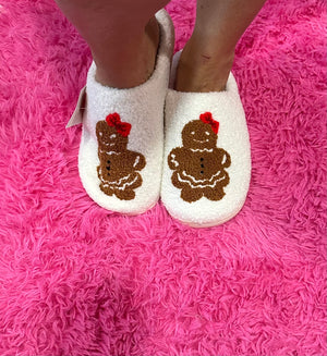 White slippers with gingerbread man design on a pink fuzzy surface