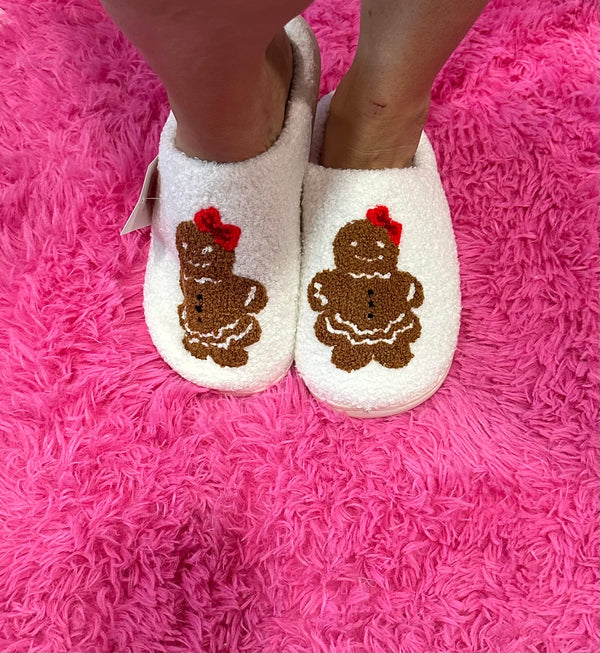 White slippers with gingerbread man design on a pink fuzzy surface