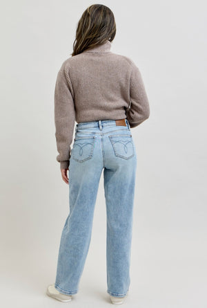Person wearing a brown sweater and light blue jeans on a plain background