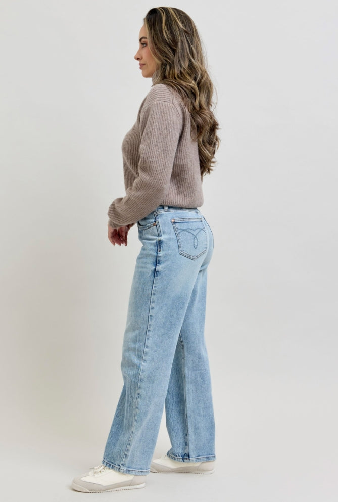 Woman wearing a brown sweater and light blue jeans on a white background