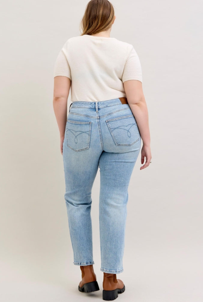 Person wearing light blue jeans and a white t-shirt on a plain background