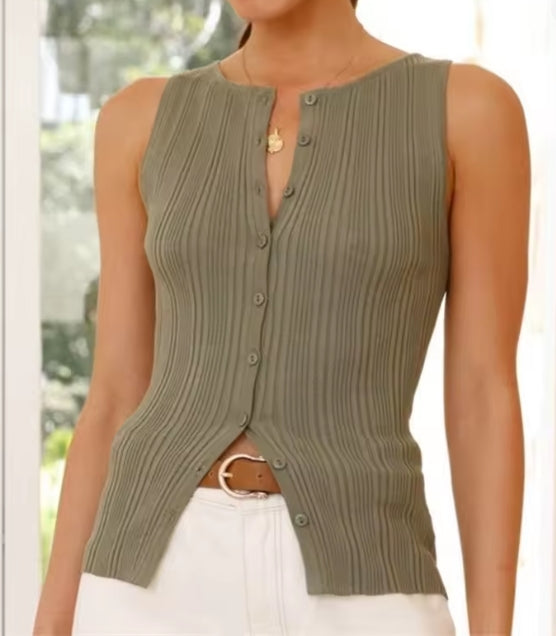 Person wearing a green ribbed knit vest over a white top.