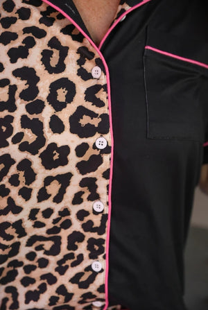 Leopard print pajama top with pink piping on a plain background