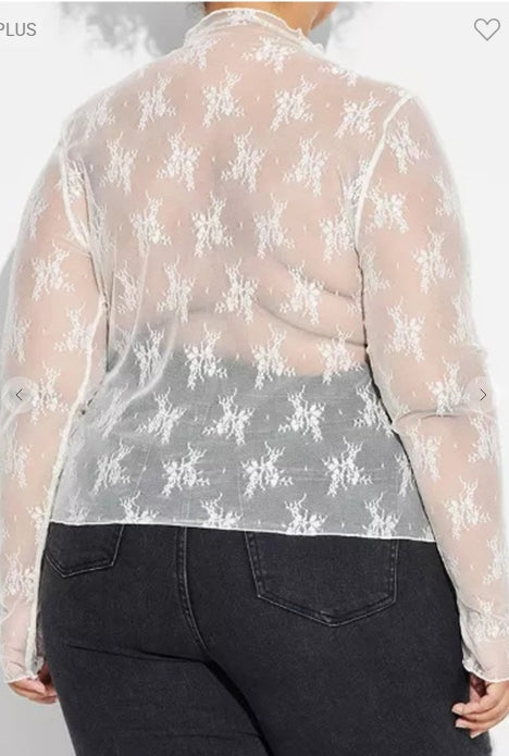 Sheer floral blouse worn over dark jeans on a plain background