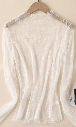 White lace top on a hanger against a beige background