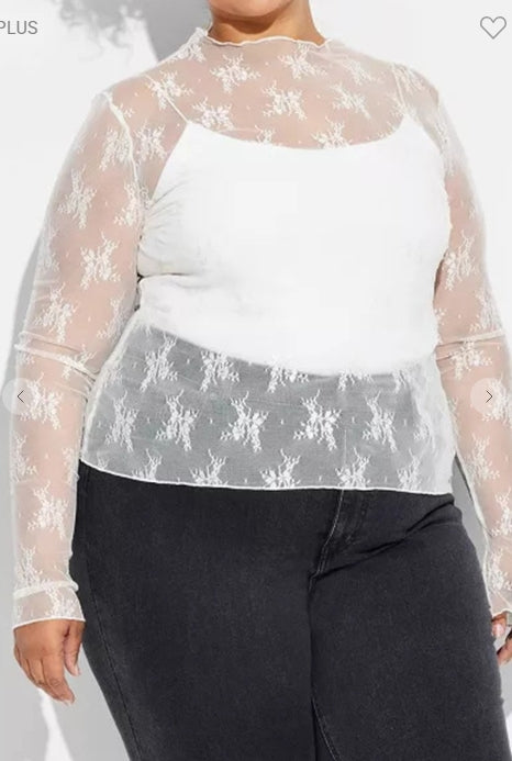Person wearing a sheer floral top over a white shirt with black pants on a plain background