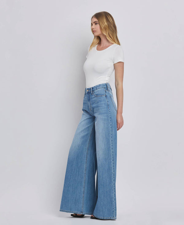Woman wearing a white t-shirt and blue jeans on a plain background