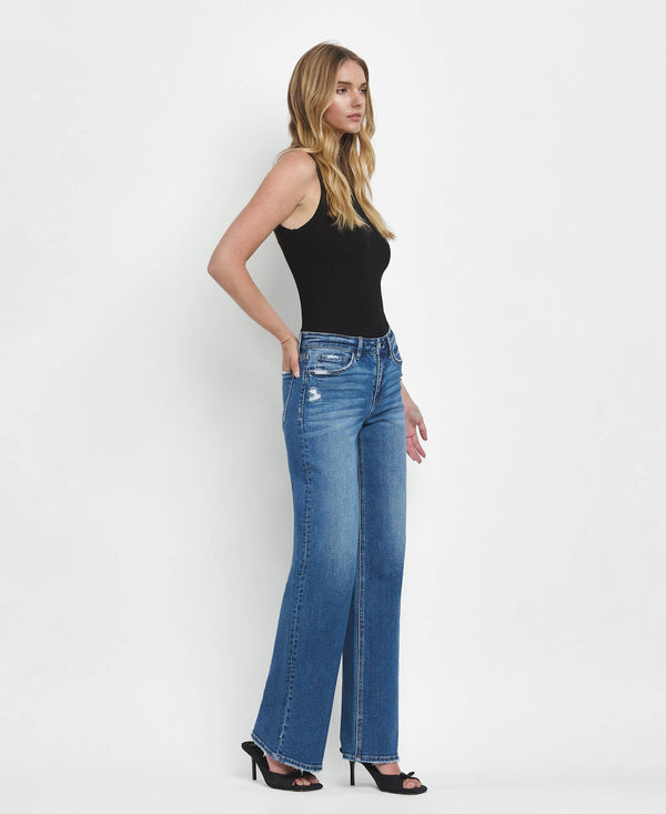 Woman wearing blue jeans and a black top on a white background