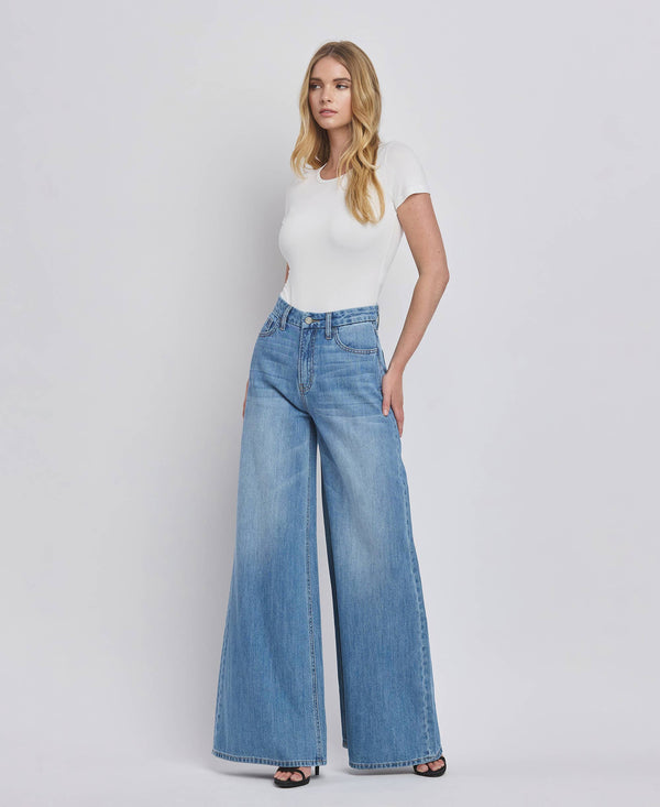 Woman wearing a white top and blue jeans on a plain background