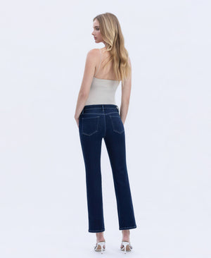 Back view of woman wearing dark wash straight-leg jeans with a mid-rise fit, styled with a neutral sleeveless top and heels.