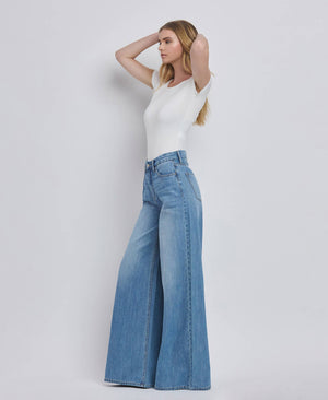Woman wearing a white top and blue jeans on a plain background
