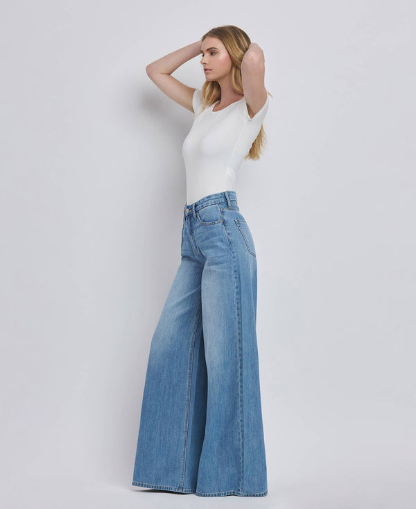 Woman wearing a white top and blue jeans on a plain background
