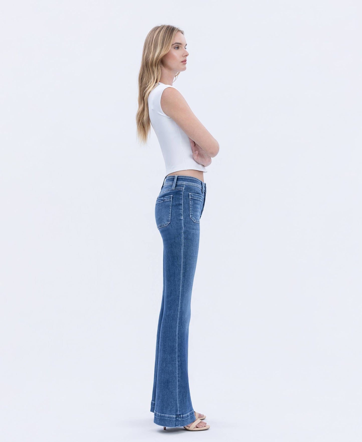 Woman wearing blue jeans and a white top on a white background