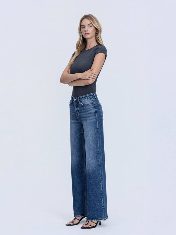 Woman wearing a black top and blue jeans on a white background