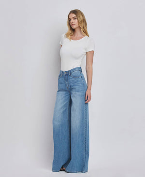 Woman wearing a white top and blue jeans on a plain background