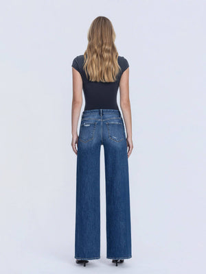 Woman wearing blue jeans and a black top on a white background