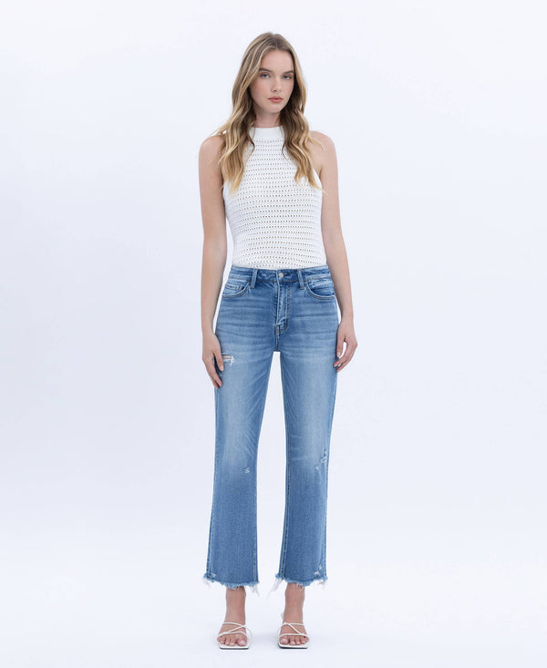 Woman wearing a white sleeveless top and blue jeans on a white background