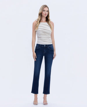 Front view of woman wearing dark wash straight-leg jeans with a mid-rise fit, paired with a ruched neutral sleeveless top and heels.